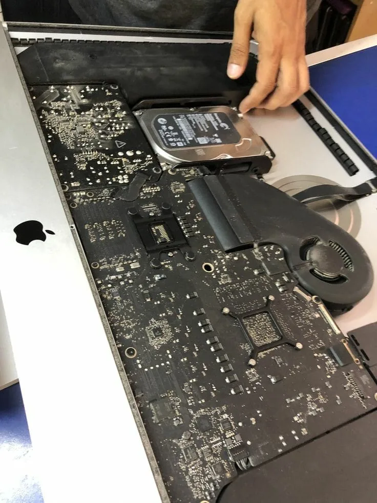 Technician working on a MacBook logic board and storage drive